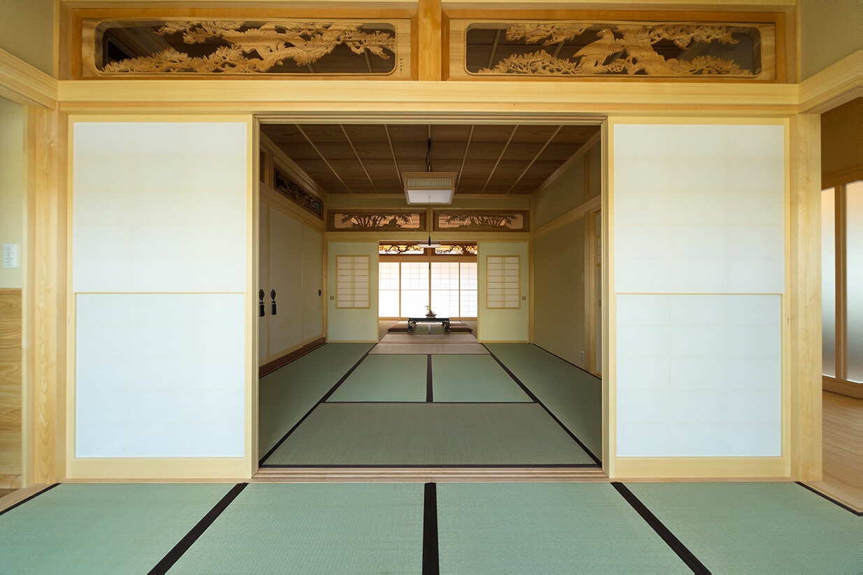 伝統的な和室が2部屋連なり、手前の部屋から奥の部屋を見通す。障子や木彫りの欄間が特徴。