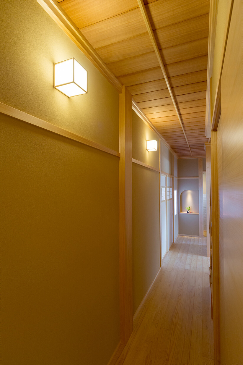 木製の天井と壁のパネルで構成された、和風でモダンな長い廊下