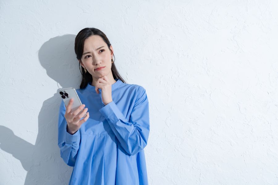 スマホを手に考える女性