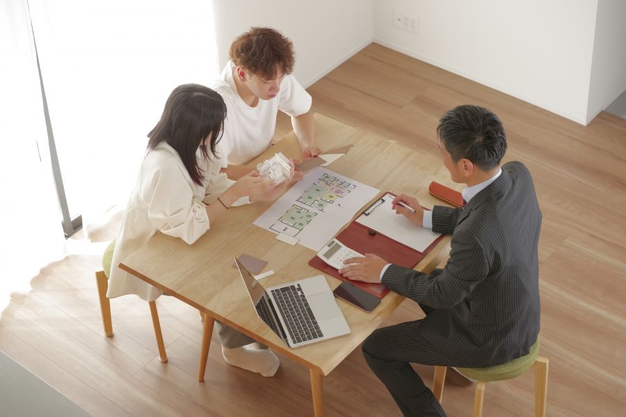 図面を広げて打合せする営業マンと若い夫婦