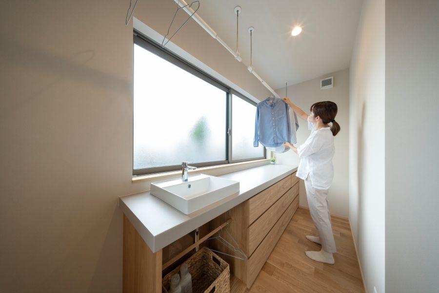 ランドリールームで洗濯物を干す女性