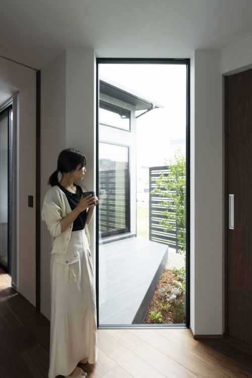 窓辺でカップを持って佇む女性