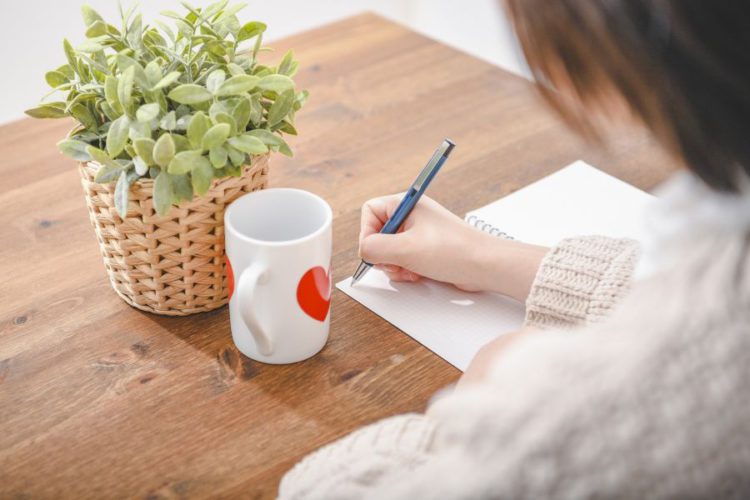 テーブルに向って書き物をする女性